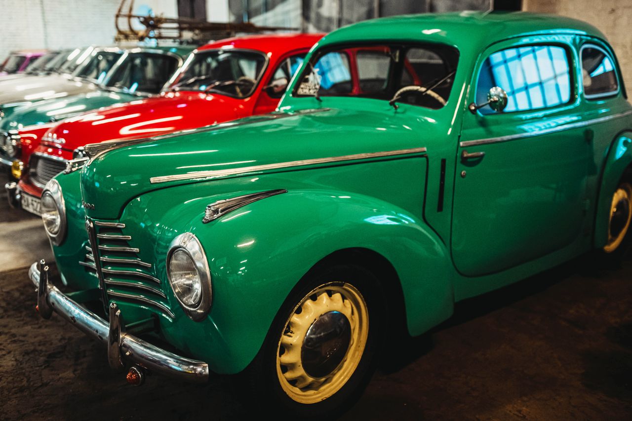 Home Collection of classic vintage cars parked in an indoor garage setting, showcasing vibrant colored vehicles.